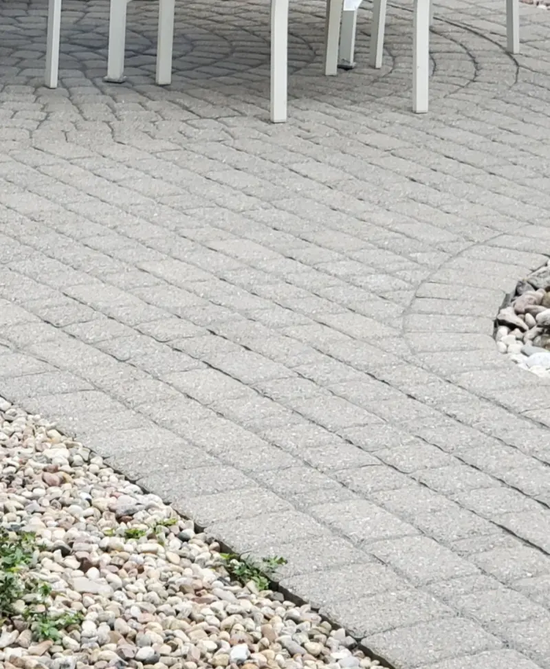 Cleaned light-grey paver patio with clear joints and a tidied gravel border