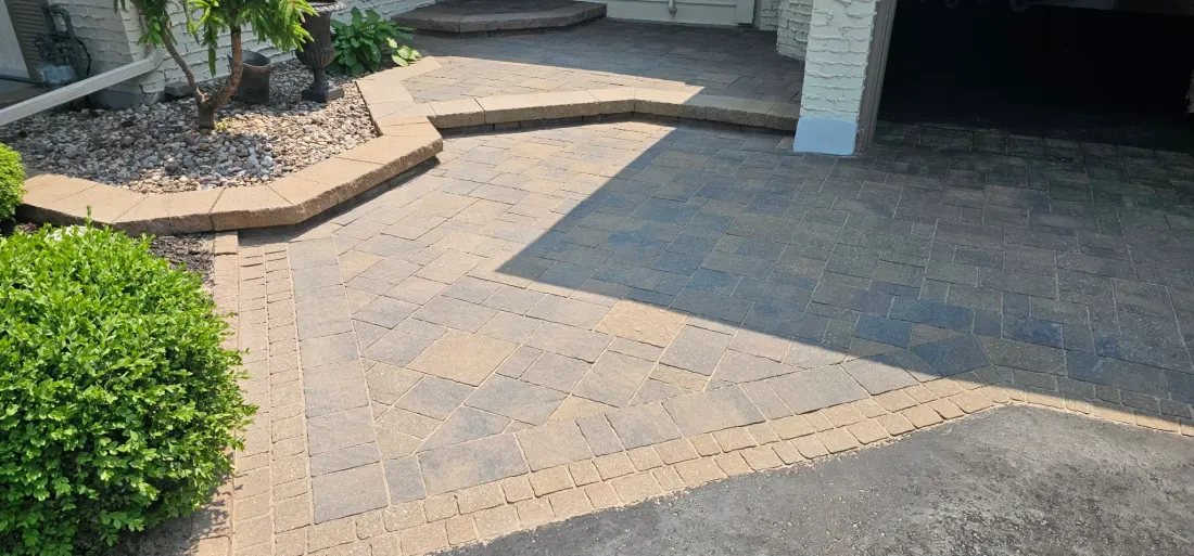 Front entry courtyard after CAT5 in full sun — rich two-tone paver colour, clean sand lines