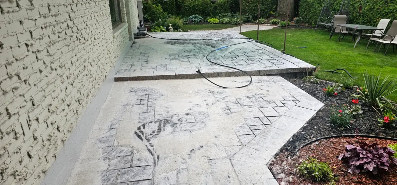 Patio mid deep-clean, white cleaning foam blanketing the pavers