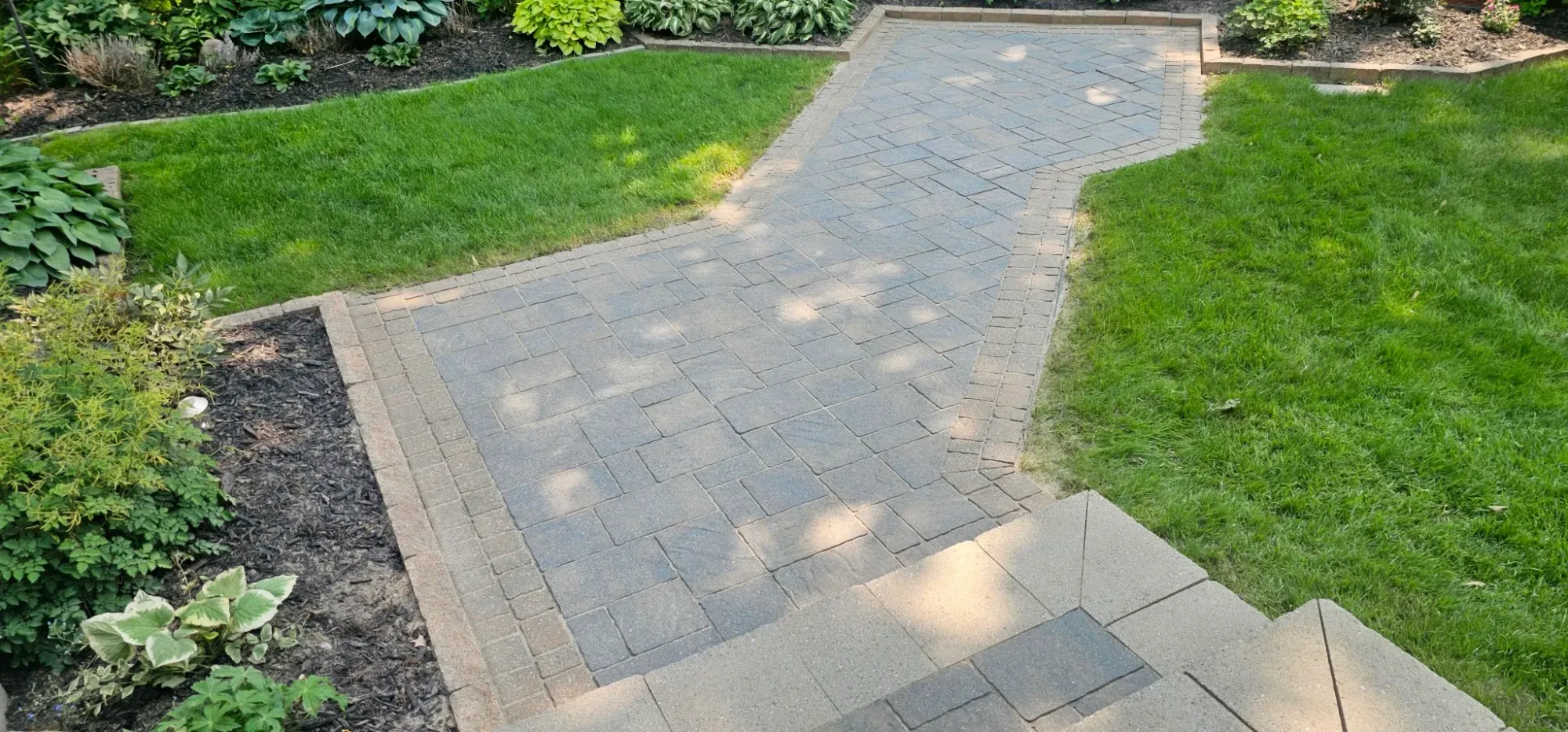 S-curve walkway restored and re-sanded but unsealed — flat grey-tan pavers