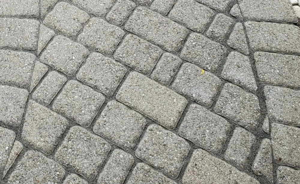 Close-up of interlock pavers with eroded, unfilled joints before re-sanding