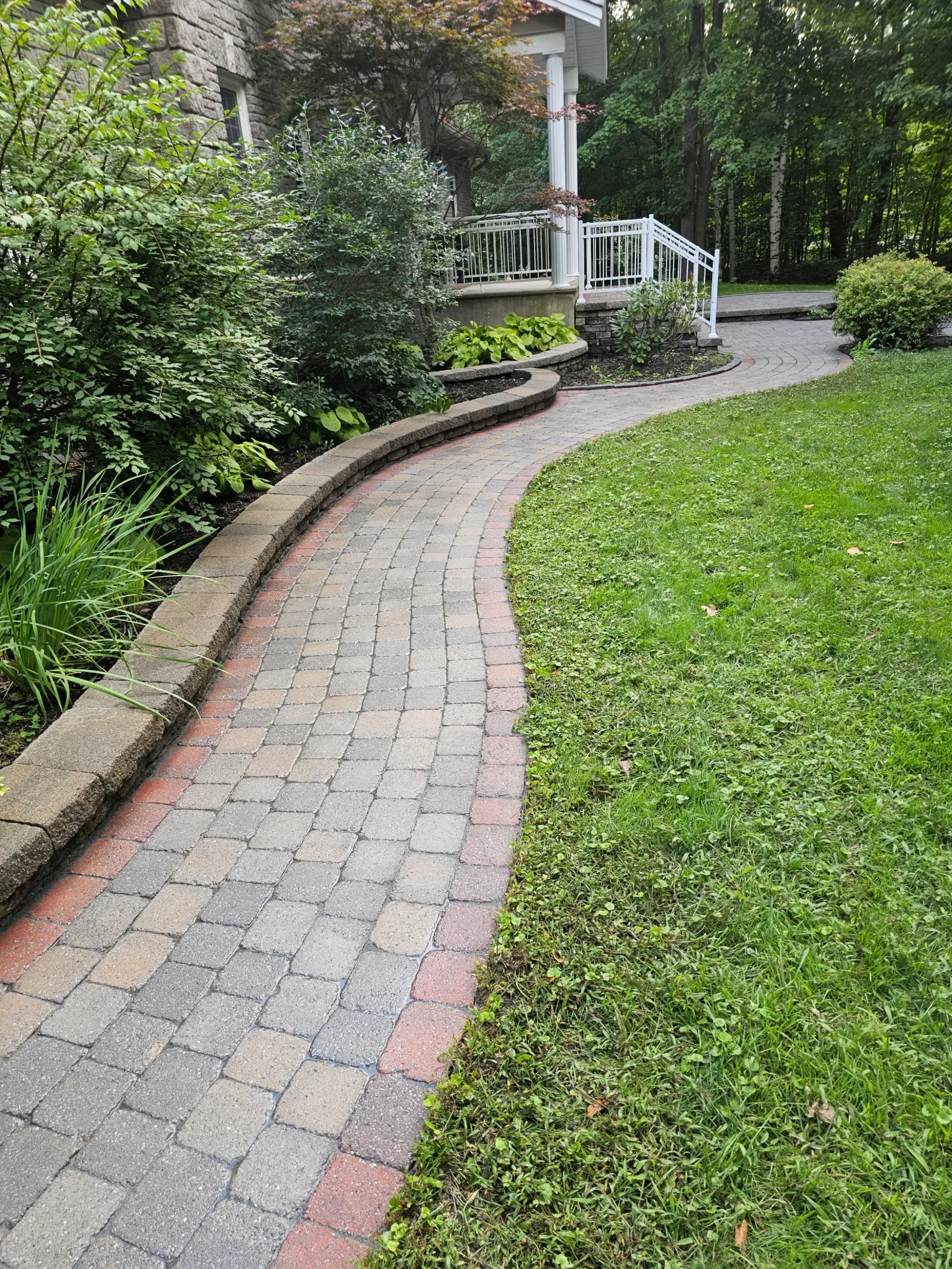 The same curved walkway restored — cleaned tumbled pavers, crisp lawn edge