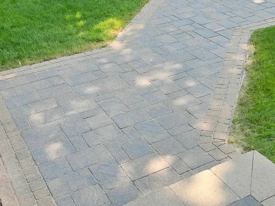 Re-sanded walkway pavers with the joints filled flush, tan soldier-course border and lawn beyond