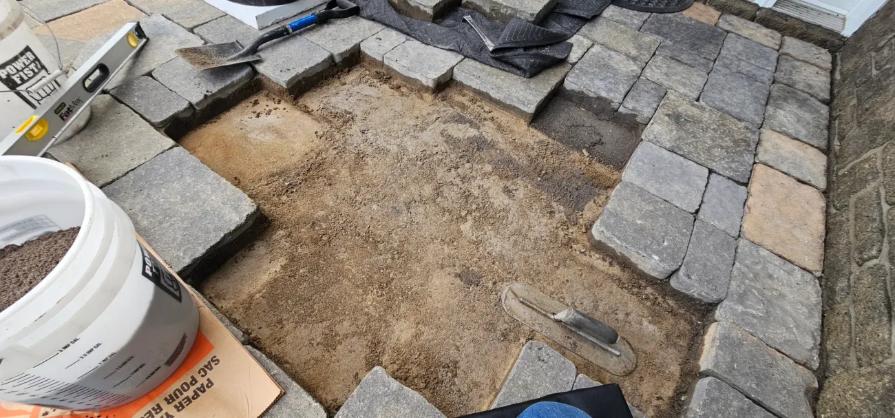 Screeded bedding with level, trowel and limestone screenings ready for relay